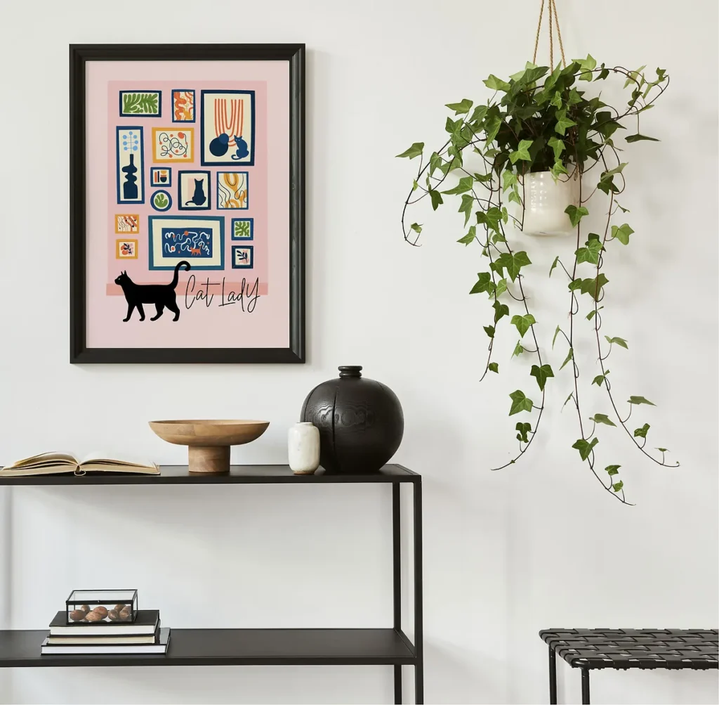 Stylized pink poster with the text 'Cat Lady' featuring a black cat silhouette walking in front of a colorful gallery wall of abstract art and botanical prints.