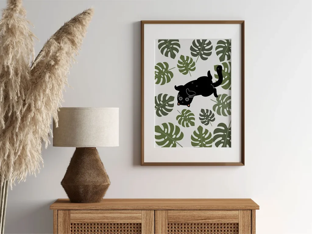 Framed botanical poster art featuring a naughty black cat hiding among large green monstera leaves and houseplants in a boho-style wooden frame